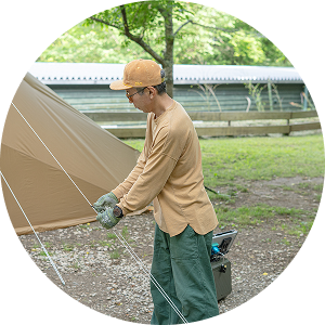 キャンプ場にゆっくりチェックインし、テント設営する男性の様子